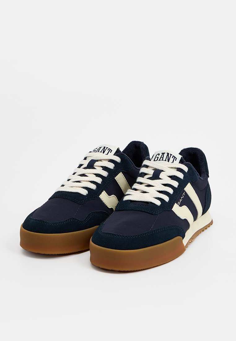Sneakers blu navy con accenti bianchi, caratterizzati da una tomaia testurizzata, lacci rotondi e una suola in gomma naturale. Nome del marchio visibile sulla linguetta.