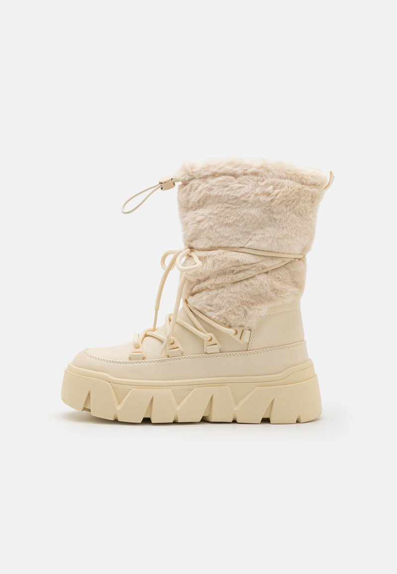 Beige, hoge winterlaars met een met bont gevoerde bovenkant, flexibele vetersluiting en een dikke, geribbelde plateauzool.