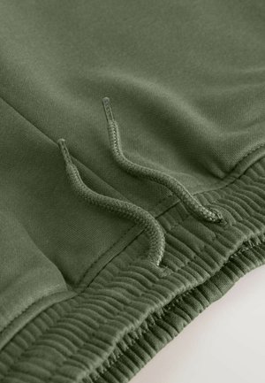 Khaki green sweatpants featuring a smooth texture, elastic waistband, and visible drawstring for adjusting fit.