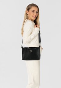 Zwarte leren handtas met een gestructureerd ontwerp, voorzien van zilverkleurige hardware, een bovenhandvat en een verstelbare schouderband.