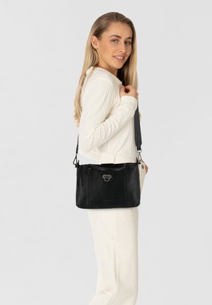 Sac à main en cuir noir avec un design structuré, featuring des accessoires en argent, une poignée supérieure et une bandoulière réglable.