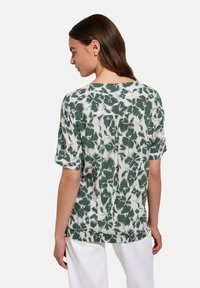 Camicetta a maniche corte in tie-dye verde e bianco con vestibilità rilassata, caratterizzata da una cucitura sul retro e un tessuto morbido e textured.