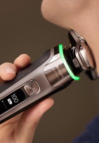 Philips 1900 Prestige elektrische scheerapparaat, ontwerp van metaal en zwart plastic, groene LED-indicator, dichtbij de huid, met display en aan-knop.