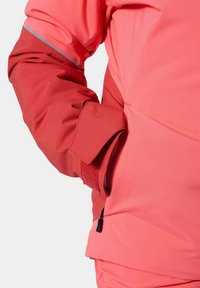 Giacca rosa brillante resistente alle intemperie con polsini in velcro, dettagli riflettenti e una tasca laterale con zip per un'immagazzinamento sicuro.