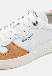 Baskets en cuir blanc avec détail en daim beige, lacets blancs et logo « Pepe Jeans London » sur le côté et la languette.