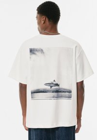Hvid bomulds T-shirt med et stort sort-hvidt hajgrafik på ryggen, med en rektangulær ramme og teksten "ERROR CODE" nedenfor.