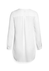 Blouse blanche à manches longues avec une texture lisse, des poignets boutonnés et un ourlet arrondi. Présente une couture centrale le long du dos.