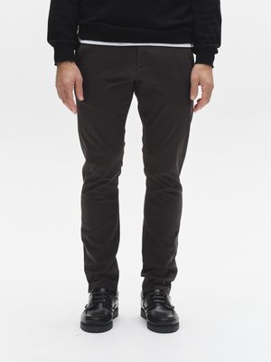 Sötétbarna, karcsúsított nadrág könnyű anyagból, sima textúrával és oldalzsebekkel, fekete fűzős cipővel párosítva.