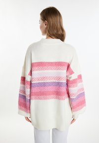 Maglione oversize color crema con motivo a righe rosa, lilla e bianco. Realizzato in un morbido tessuto testurizzato. Presenta spalle scese e un colletto a costine.