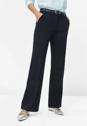 Pantalons coupe large marine en tissu lisse, dotés de poches avant et d'une ceinture, associés à des ballerines argentées pour un look complet.
