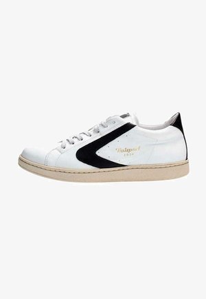 Baskets blanches avec accents noirs, tige en cuir lisse, panneau texturé, bout rond, design à lacets, semelle en caoutchouc, détails de logo en or.