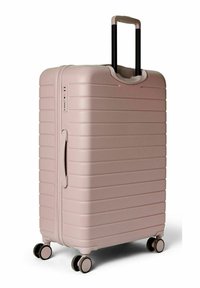 Valise rigide rose avec textures nervurées, poignée extensible noire, poignées latérales doubles et quatre roues pivotantes pour une mobilité aisée.