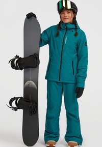 Teal snowboardjack en -broek van gestructureerde stof, gecombineerd met een zwarte snowboard met bindingen en een maanontwerp.