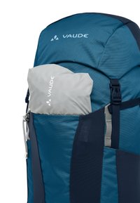 Zaino blu con tasca pieghevole grigia nella tasca esterna in rete. Presenta un logo, cerniere e spallacci regolabili. Realizzato in tessuto resistente.