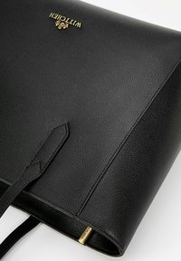 Černá kožená taška přes rameno s texturovaným povrchem, která má zlaté logo a strukturovaný design. Je vybavena dvojitými uchy a hladkým podšívkovým materiálem.