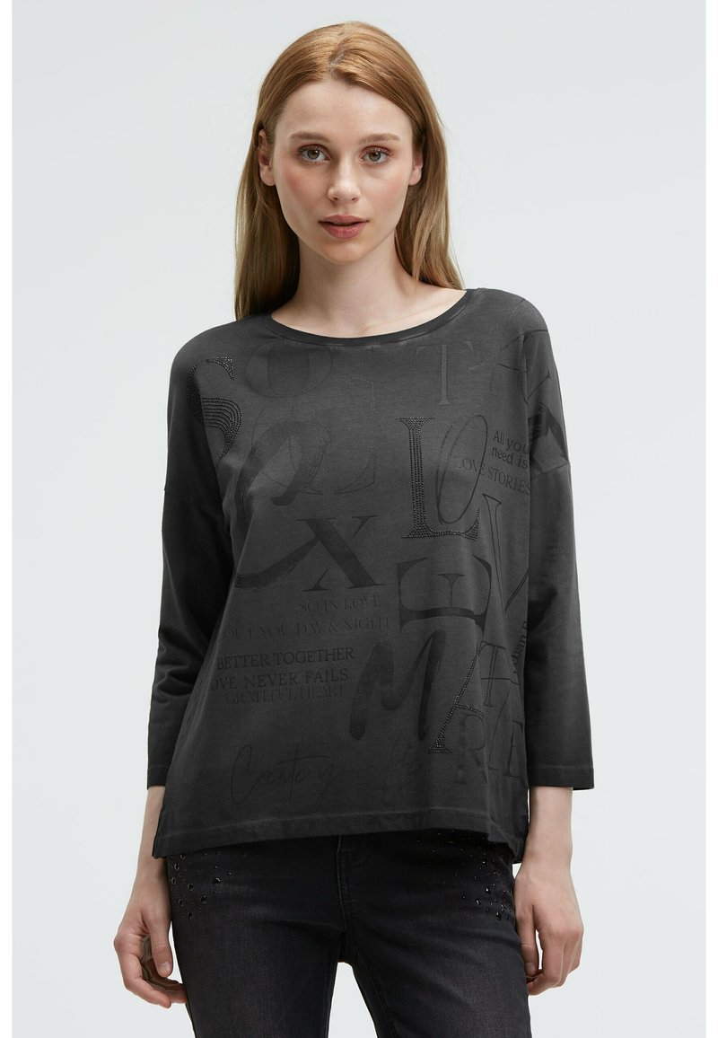 Black long-sleeve T-shirt featuring varying typography and embossed text. Soft fabric with a relaxed fit and round neckline. Text includes phrases.