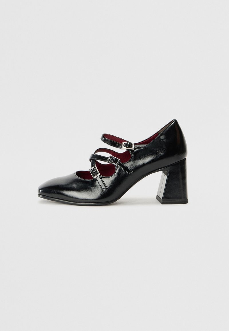 Chaussure Mary Jane en cuir verni noir avec trois brides réglables à boucle et talon carré, vue de côté sur fond blanc.