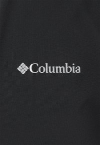 Tela negra con una textura suave que presenta un logo plateado de "Columbia" y un acento de patrón en forma de diamante cerca del nombre de la marca.