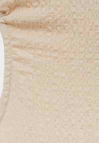 Tissu beige texturé avec un motif de froissement subtil, présentant des lignes douces et légèrement surélevées, créant une apparence tactile.