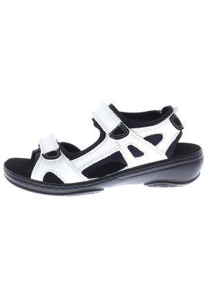 White leather sandal with black accents, adjustable hook-and-loop straps, open design, cushioned footbed, and a durable black sole.