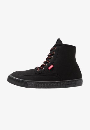 Zapatilla negra tipo bota de lona con cordones rojos y negros, suela de goma texturizada y etiqueta con el logo rojo de Levi's en el lateral.