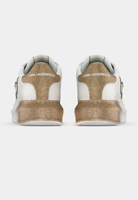 Biały sneaker z teksturowanym złotym akcentem na pięcie, z wytłoczonym nazwiskiem marki „Karl Lagerfeld” na tyle.