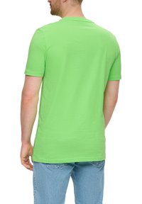 Groene katoenen t-shirt met korte mouwen, ronde hals en een soepele textuur. Gekocht met lichtblauwe spijkerbroeken.