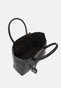 Svart enaxlad väska med texturerade sidor, två handtag, tryckknappsstängning, inre zipficka och bifogad rektangulär hängande etikett.