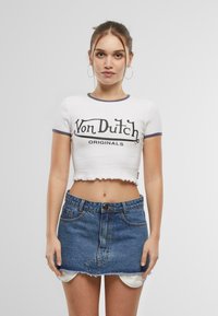 White cropped t-shirt with navy accents and "Von Dutch ORIGINALS" graphic, paired with a denim mini skirt featuring a frayed hem.