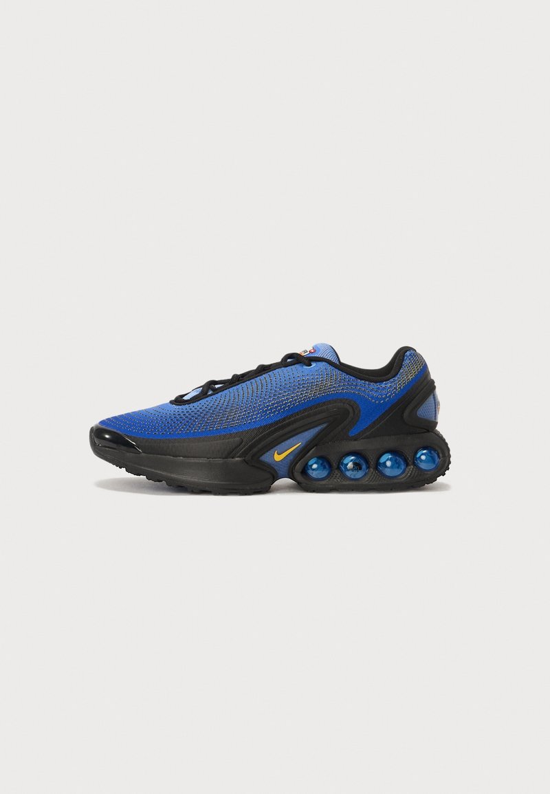 Baskets de sport bleues et noires avec des lacets noirs, logo Nike jaune et quatre coussins d’air bleus dans la semelle, montrées de profil sur fond blanc.