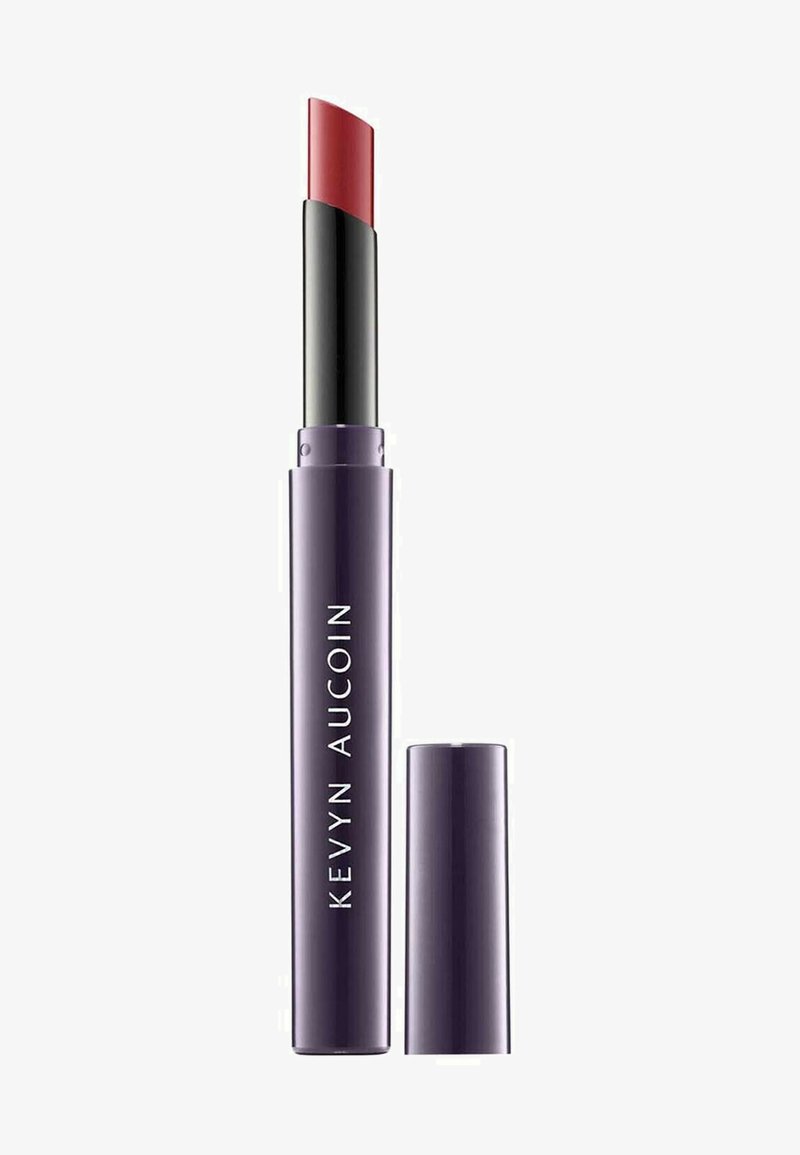 Purple lipstick tube with a curved red bullet tip, black twist-up mechanism, and white text label reading "KEVYN AUCOIN." Cap removed.