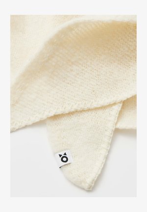 Sciarpa lavorata a maglia di colore crema con una texture morbida, caratterizzata da un bordo a onde e un'etichetta tessuta con un piccolo logo.