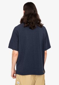 Mørkeblå kortærmet t-shirt med løs pasform, raglanærmer og en glat tekstur. Klippet har en lige kant og minimal detaljering.