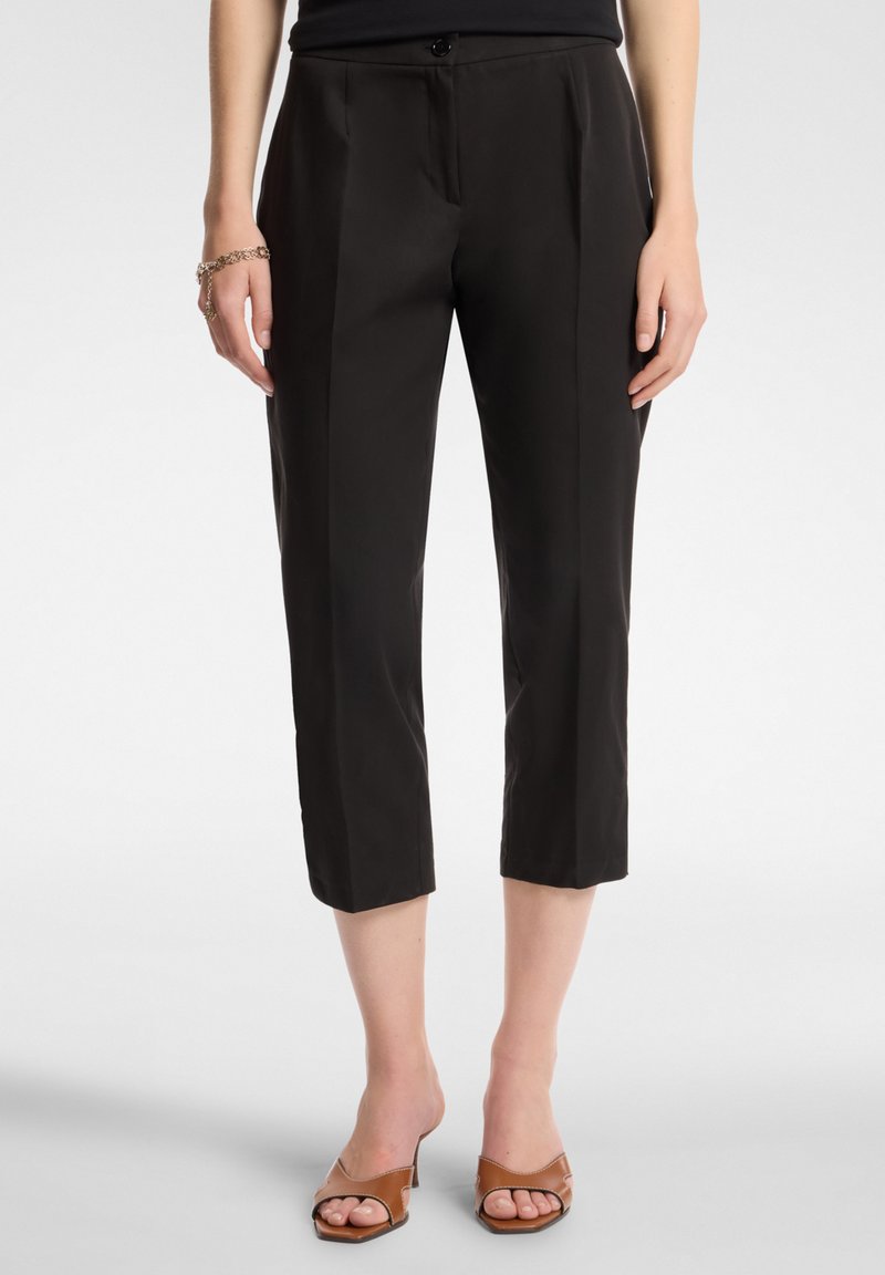 Pantaloni neri su misura realizzati in tessuto morbido, caratterizzati da una vestibilità slim e una lunghezza cropped. Presentano una chiusura con bottone e pieghe frontali.