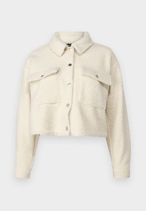 Giacca in pile color crema con un design corto, chiusura con bottoni, due tasche frontali e colletto classico. Tessuto morbido e texture.