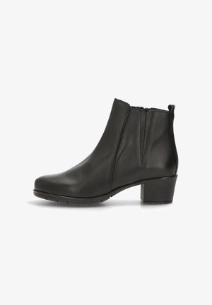 Bota de tobillo de cuero negro con punta redonda, costura mínima, gomas laterales y un tacón grueso. La suela de goma proporciona tracción.