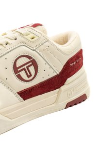 Krēmveida ādas tenisa apavi ar bordo zamšiem, apaļu logotipu, teksturētu apdari un bēša auklām; mīkstais apkaklis un gumijas zole.