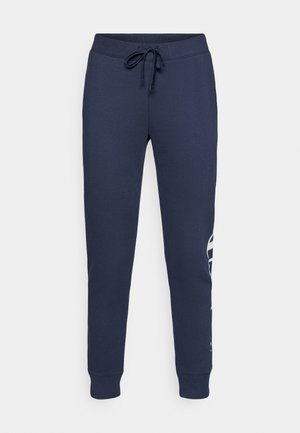 Mørkeblå joggebukser laget av mykt materiale, med snor i livet, smale ben og en fremtredende hvit logo på siden.