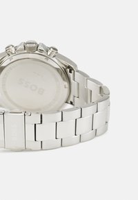 Reloj de acero inoxidable plateado con pulsera pulida, caja redonda y funciones de cronógrafo. Grabado "BOSS" en el cierre y en la parte trasera de la caja.