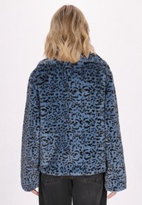 Umělá kožešinová bunda s modro-černým leopardím vzorem, oversize střih, spadlé ramena a dlouhé rukávy. Zadní pohled ukazuje texturu a design.