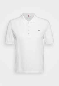 Vit pikétröja i bomull med klassisk krage, tre knappar, korta ärmar och en liten broderad logotyp på bröstet.