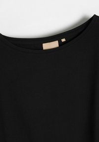 Czarna koszulka z okrągłym dekoltem, wykonana z miękkiej bawełny. Posiada dyskretną metkę w kolorze beżowym z napisem "diverse" oraz rozmiar "M" z tyłu.