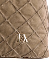 Bolso de tela acolchada color topo con textura suave, con el logo "DA" en tono dorado. Patrón de rombos cosido de manera ordenada en toda la superficie.