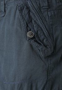 Marinblå cargoshorts med en sidficka, med knäppning och kontrasterande sömmar. Tillverkade av lättviktig tyg.