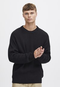 Pulover negru din tricot cu model cu nervuri, cu guler rotund și umeri lăsați. Dispune de mâneci lungi și o croială confortabilă. Model simplu, texturat pe întreaga suprafață.