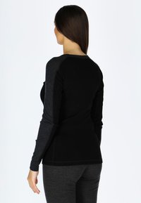 Zwarte lange mouw top met donkergrijze raglan mouwen, aansluitend ontwerp, gladde textuur en een ronde hals. Draagt bijpassende donkergrijze broek.