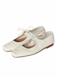 Ballerine in pelle bianca con design a intaglio, lacci sottili legati sul davanti e una texture morbida. Suola piatta con tacco minimo.