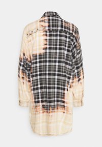 Robe chemise à manches longues à carreaux noirs et beiges avec effet délavé, vue de dos sur fond blanc.