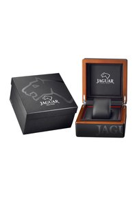 Blizgus juodas dėžutė su „Jaguar“ logotipu. Viduje yra medinė išdėstymo plokštė su juodu odiniu pagalvėliu ir raudonomis akcentais laikrodžiui.