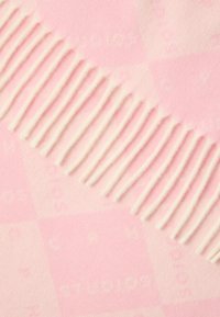 Puha tapintású, rózsaszín kockás takaró, egyik oldalán fehér rojttal és finoman a mintába integrált márkajelzéssel.